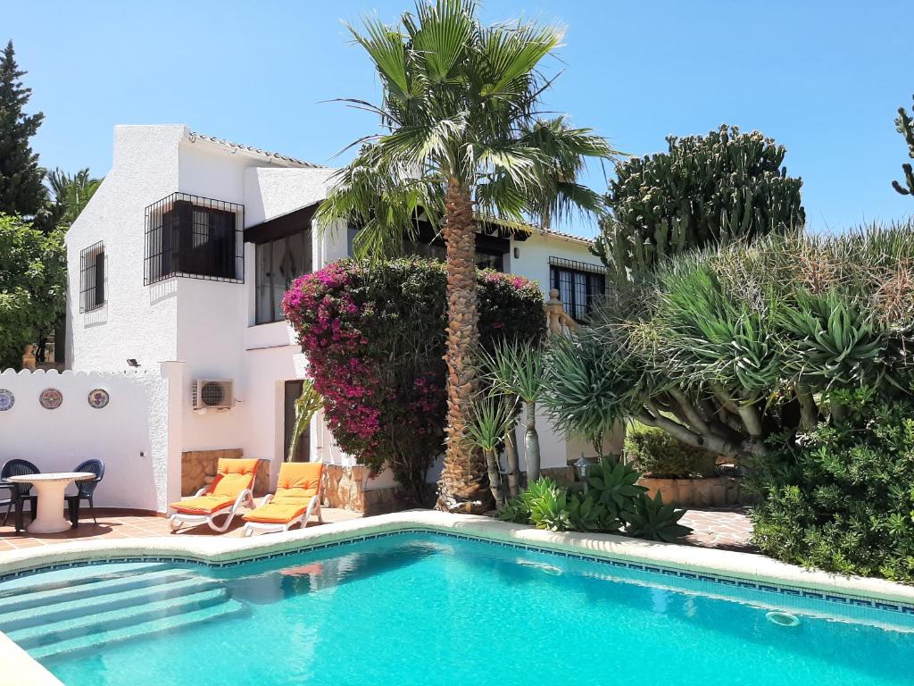 a swimming pool in front of a house with a palm tree at Villa Limon - Tropical Oasis with Private Pool in Jávea