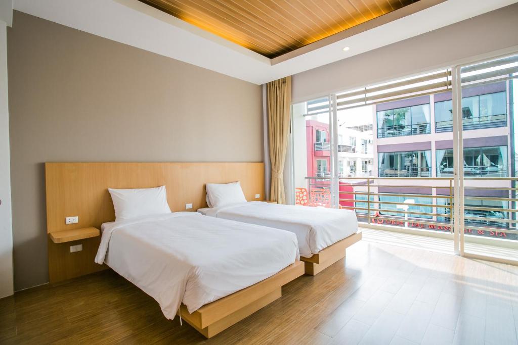 1 dormitorio con 2 camas y ventana grande en Casa de Coral Boutique Hotel, en Kata Beach