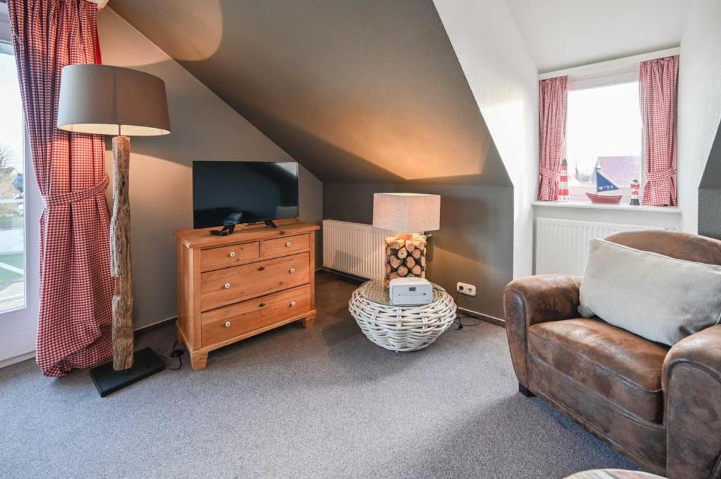 een woonkamer met een bank, een tv en een stoel bij Jule - Sonnenhof 9 in Kellenhusen