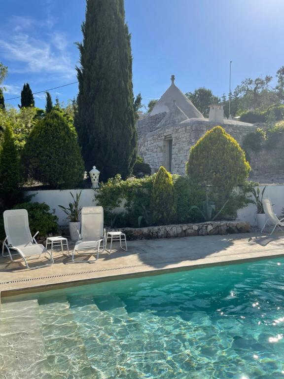 a swimming pool with two chairs and a house at Pietrefitte in Ostuni
