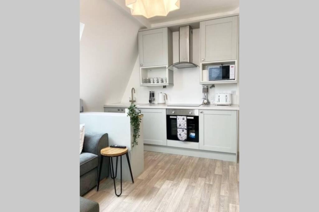 cocina con armarios blancos y mesa en Paradise St Apartment Top Floor 3 flights of stairs 3 bed 1 bathroom, en Rhyl