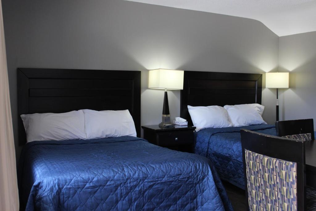 een hotelkamer met 2 bedden met blauwe lakens bij Super 7 Motel London in London