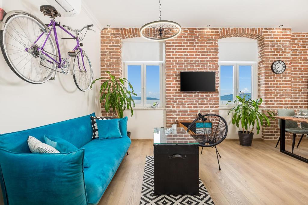 a living room with a blue couch and a bike on the wall at Apartment Vintasio in Rijeka