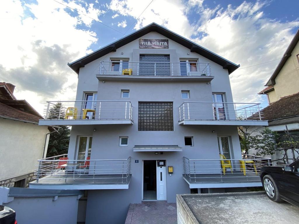 ein weißes Gebäude mit Balkon und Parkplatz in der Unterkunft Villa Vlasta in Sokobanja