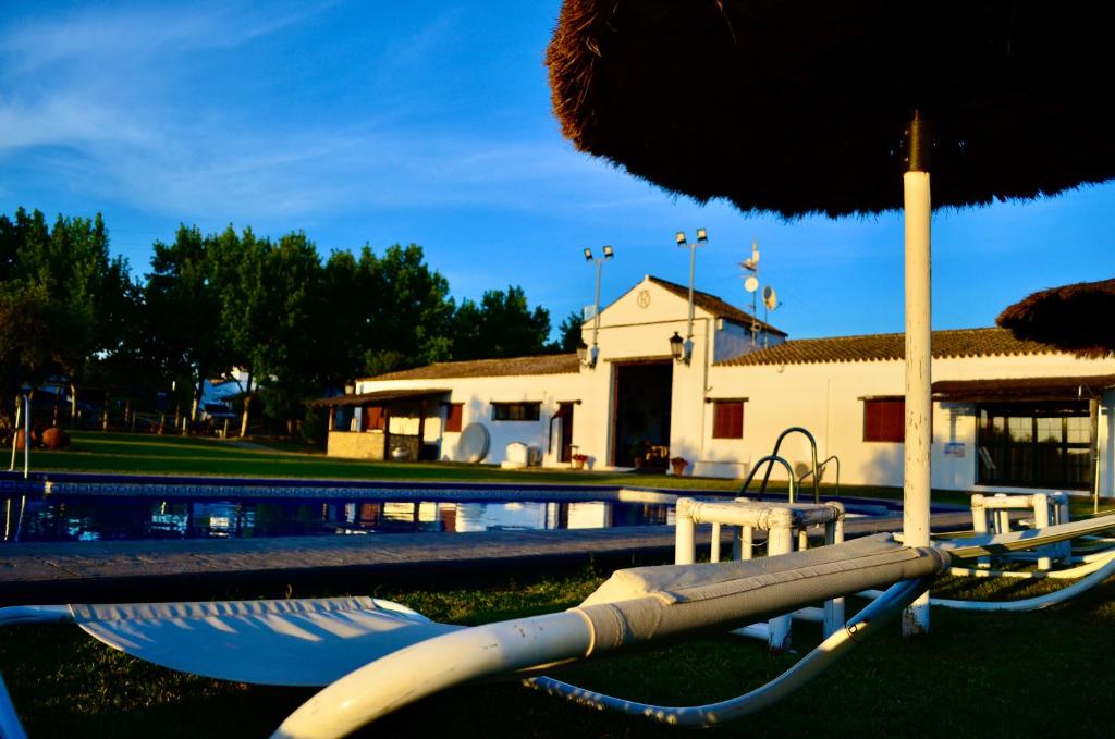 a swimming pool with an umbrella and a playground at Cortijo Mesa de la Plata in Arcos de la Frontera