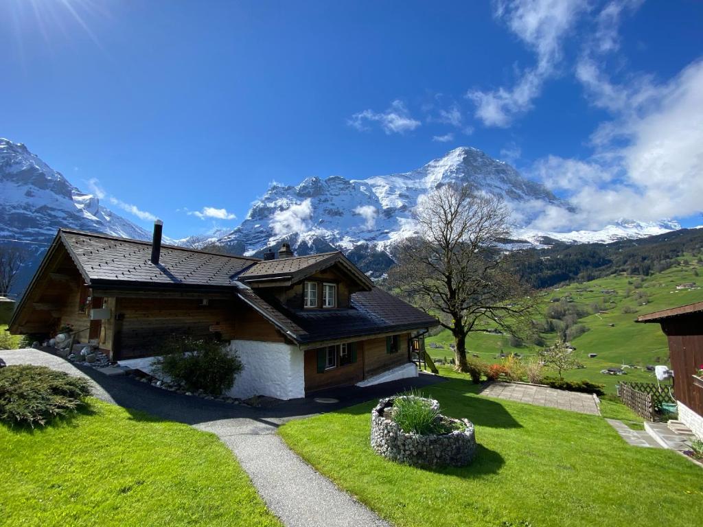 una casa en una colina con montañas en el fondo en Chalet Herrschaft, en Grindelwald