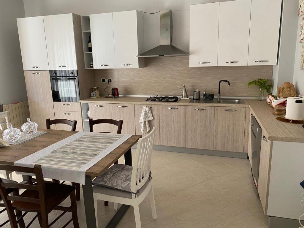 uma cozinha com armários brancos e uma mesa e cadeiras em Ciccio apartment em Bovalino Marina