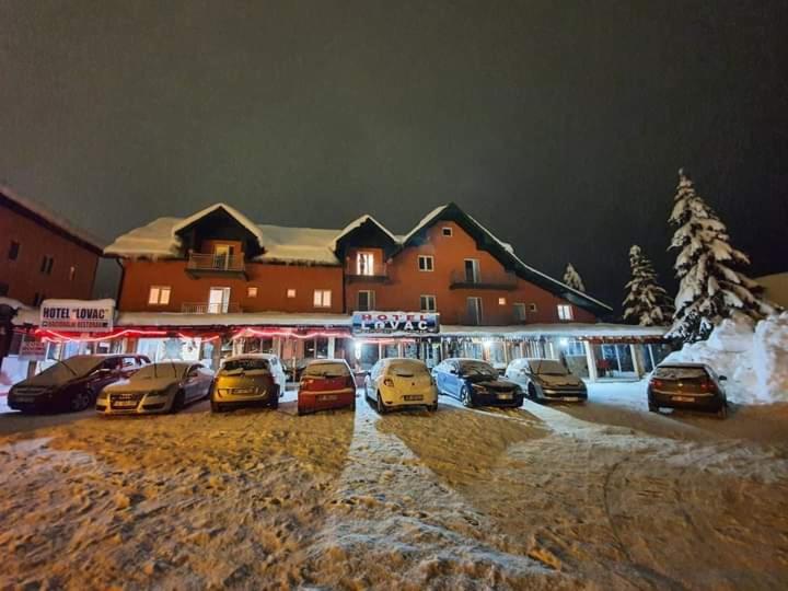 un grupo de autos estacionados en un estacionamiento frente a un edificio en Hotel Lovac, en Žabljak