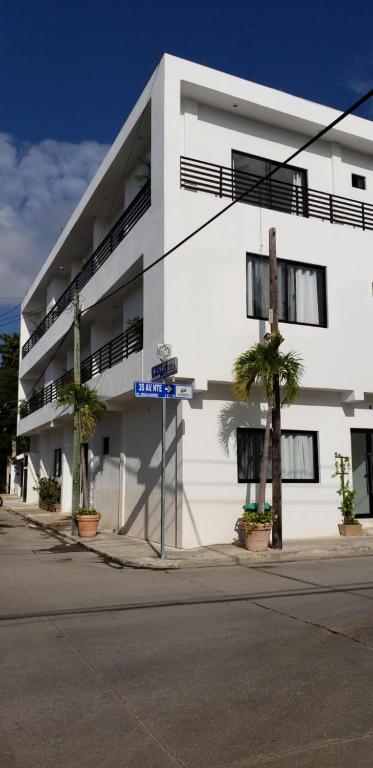 un bâtiment blanc avec des palmiers devant lui dans l'établissement SuitesMB, à Playa del Carmen