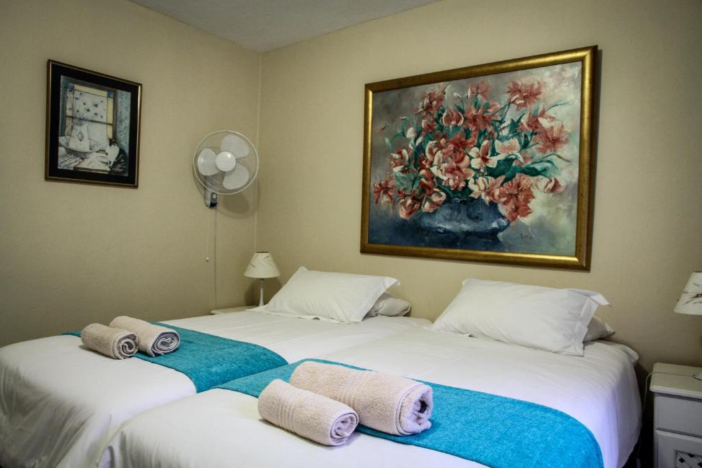 two beds in a room with a painting on the wall at Sunshine Self Catering in Nelspruit