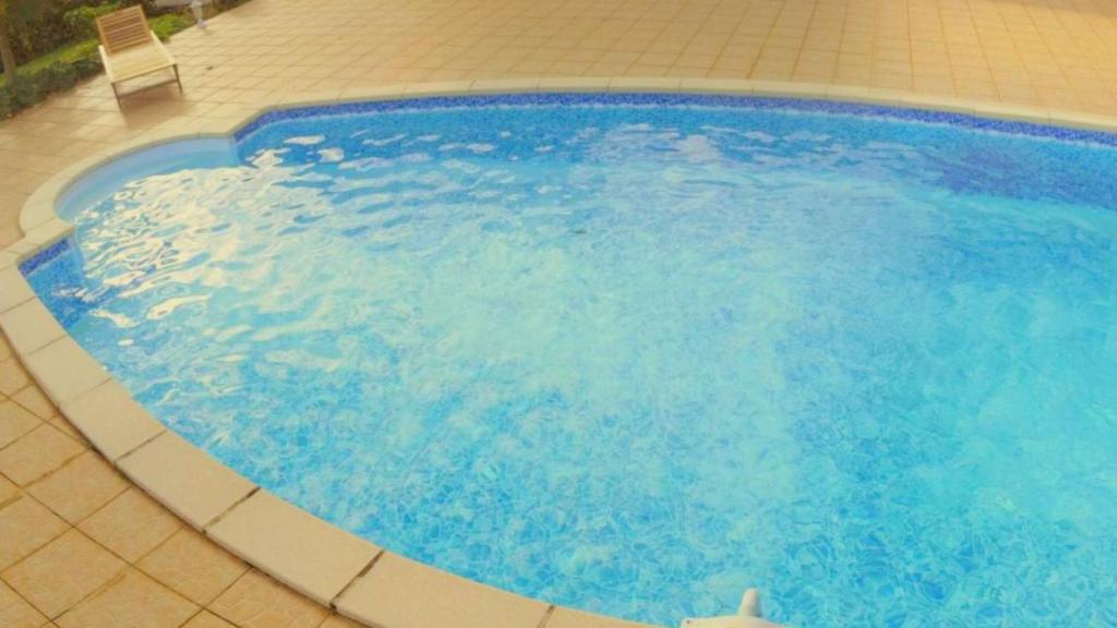 - une grande piscine bleue revêtue de carrelage dans l&#39;établissement Appartement Camillia, 41m2 et son jardin privatif., à Petit-Bourg