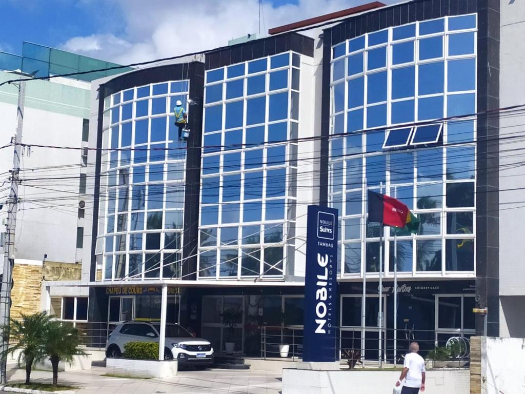 a large glass building with a car parked in front of it at Imperial Flat Tambaú - João Pessoa in João Pessoa