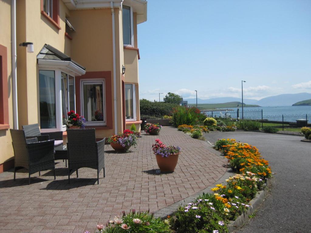 eine Terrasse mit Stühlen und Blumen vor einem Gebäude in der Unterkunft Coastline House in Dingle