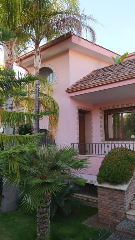 a pink house with palm trees in front of it at Casa vacanze in Casarano