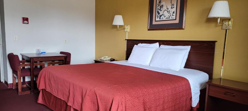 een hotelkamer met een groot bed met een rode deken bij Rodeway Inn in Goddard