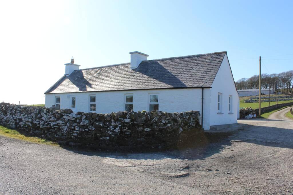 a white house with a stone wall around it at Derrie Farm Cottage in Newton Stewart