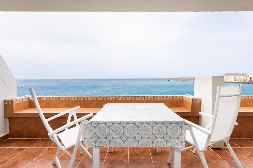 a table and chairs in a balcony with a view of the ocean at Listen the ROCKS in Costa Del Silencio