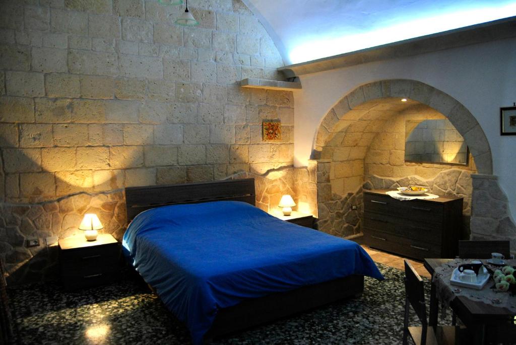 a bedroom with a blue bed and a stone wall at La Casetta in Oria