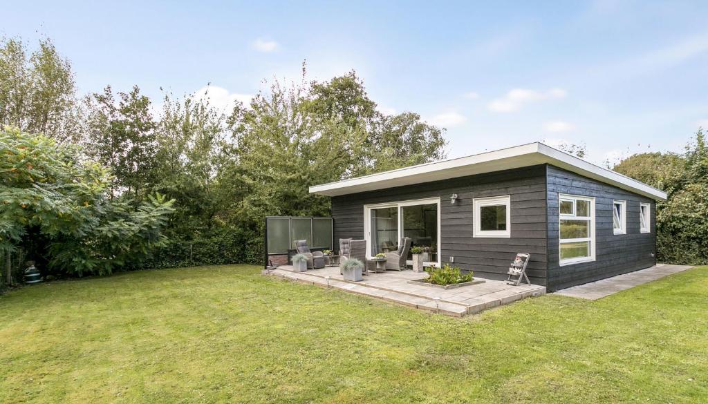 a tiny house with a deck in a yard at Prinsenhof 13 - Big, natural, fenced garden, dog friendly - not for companies in Ouddorp