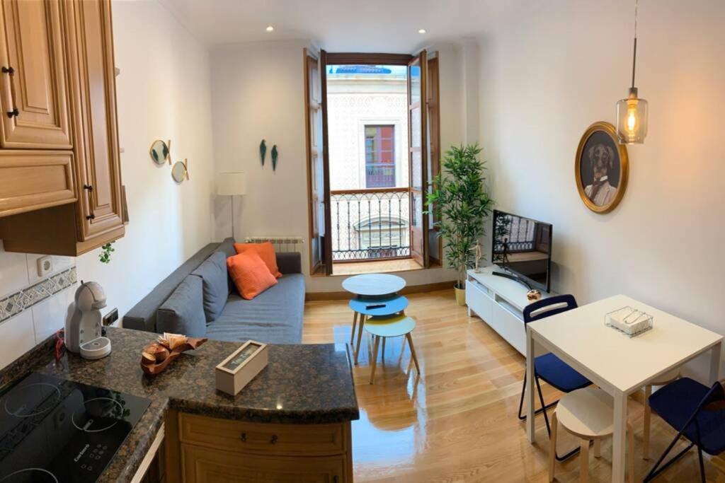 eine Küche und ein Wohnzimmer mit einem Sofa und einem Tisch in der Unterkunft LUJOSA en la plaza mayor de GIJON in Gijón