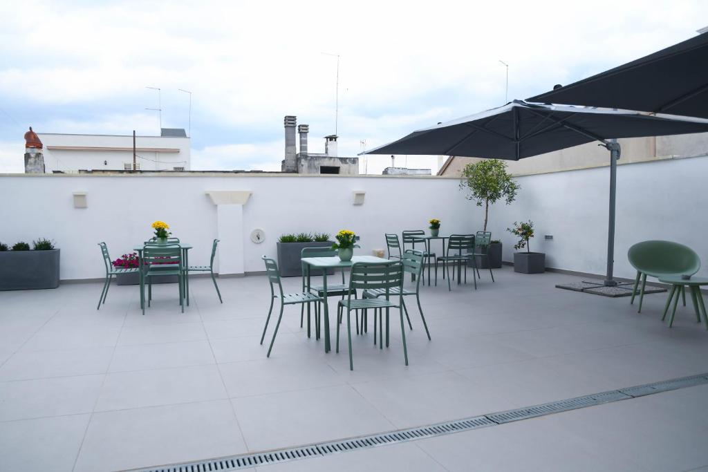 een patio met tafels en stoelen en een parasol bij B&B Benefici in Maruggio
