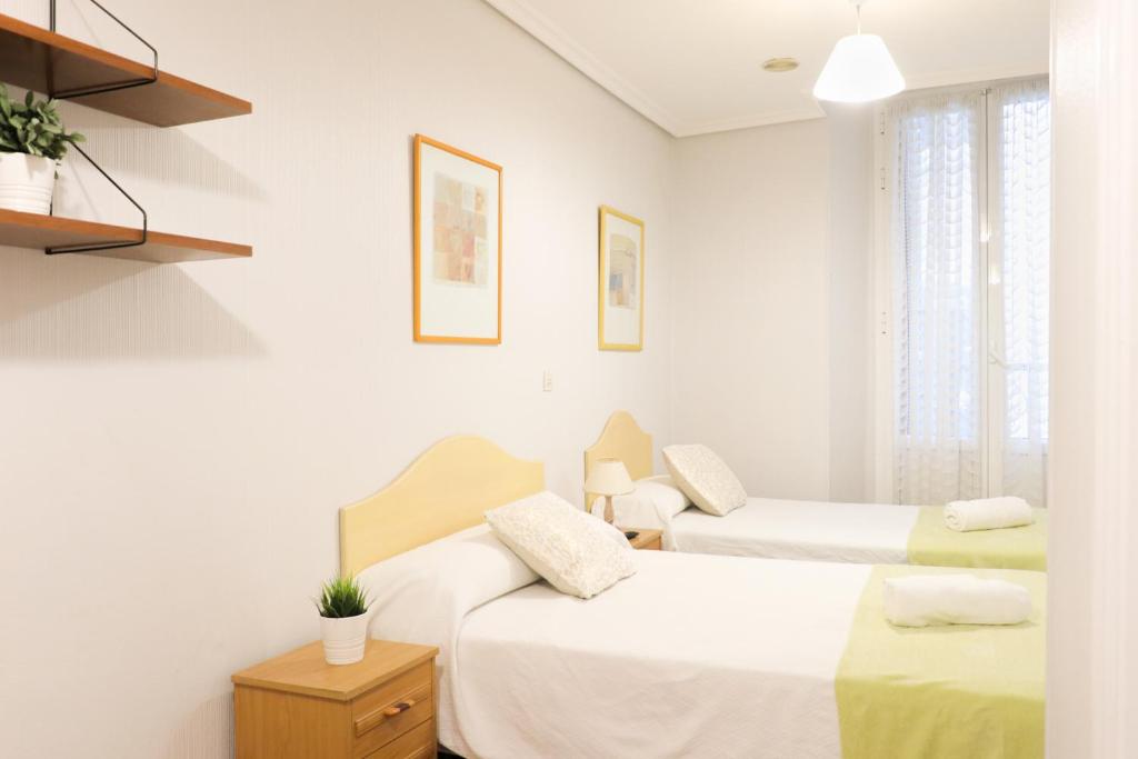 2 camas en una habitación con paredes blancas en Pensión San Lorenzo, en San Sebastián