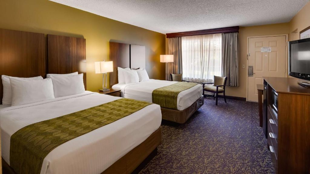 a hotel room with two beds and a flat screen tv at Best Western Plaza Inn in Pigeon Forge