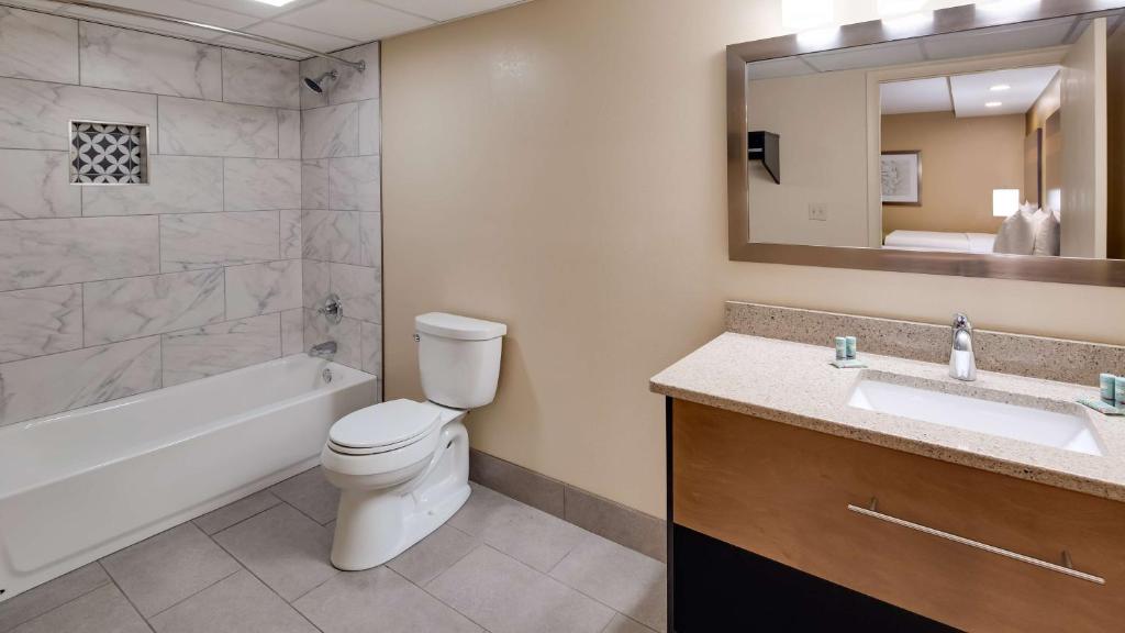 a bathroom with a toilet and a tub and a sink at Best Western Plaza Inn in Pigeon Forge