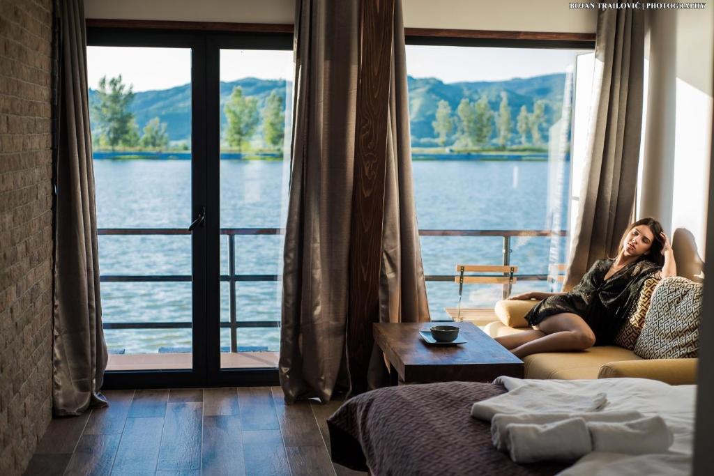 a woman sitting on a couch in front of a window at Boatel Copacabana in Veliko Gradište