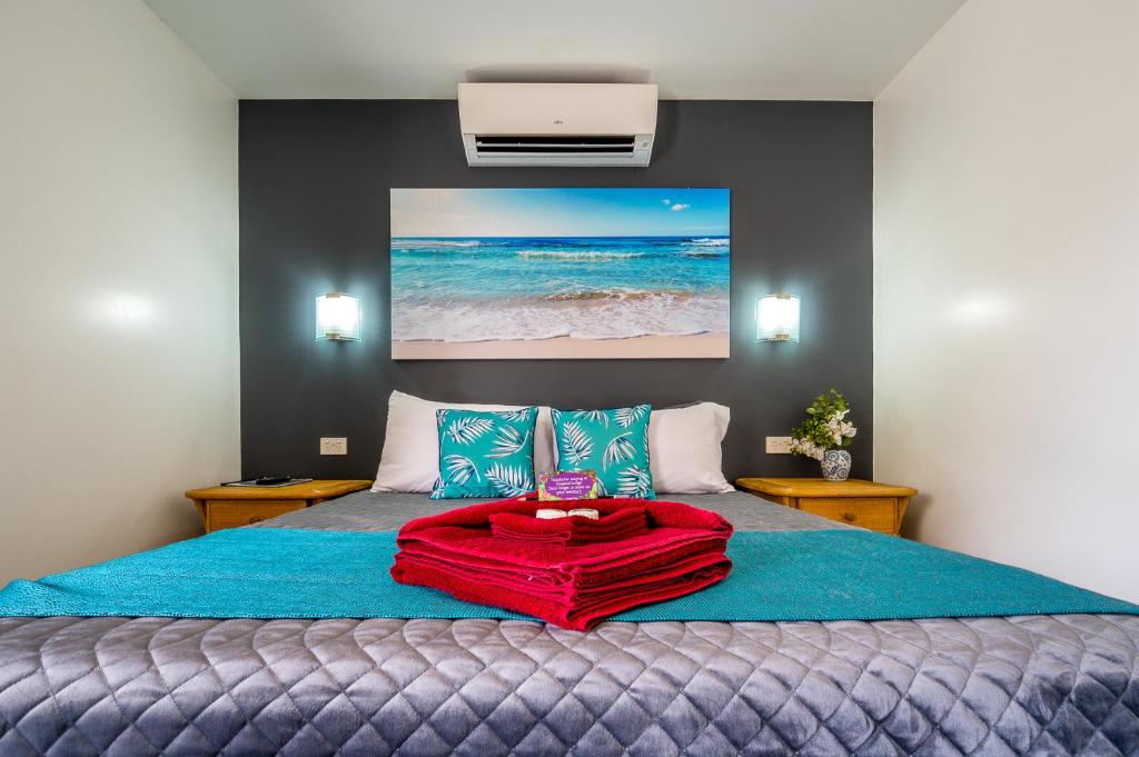 een slaapkamer met een bed met een rode deken erop bij Tropical Lodge in Innisfail
