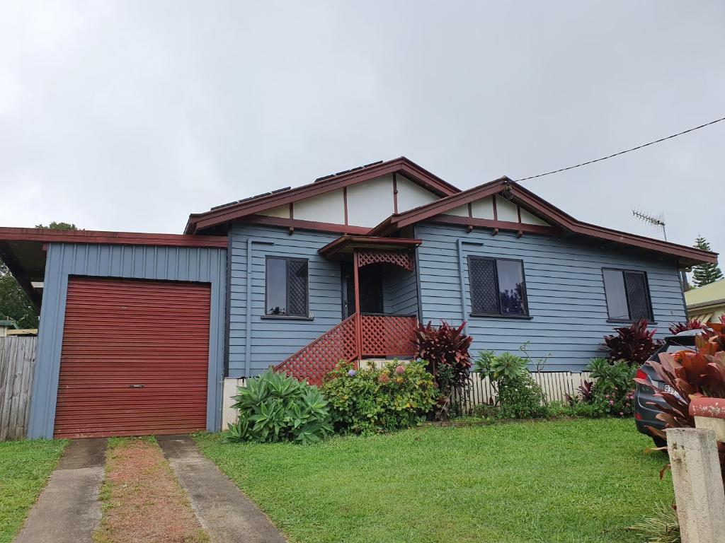 una casa azul con garaje rojo en Cottage on Herbert en Ravenshoe