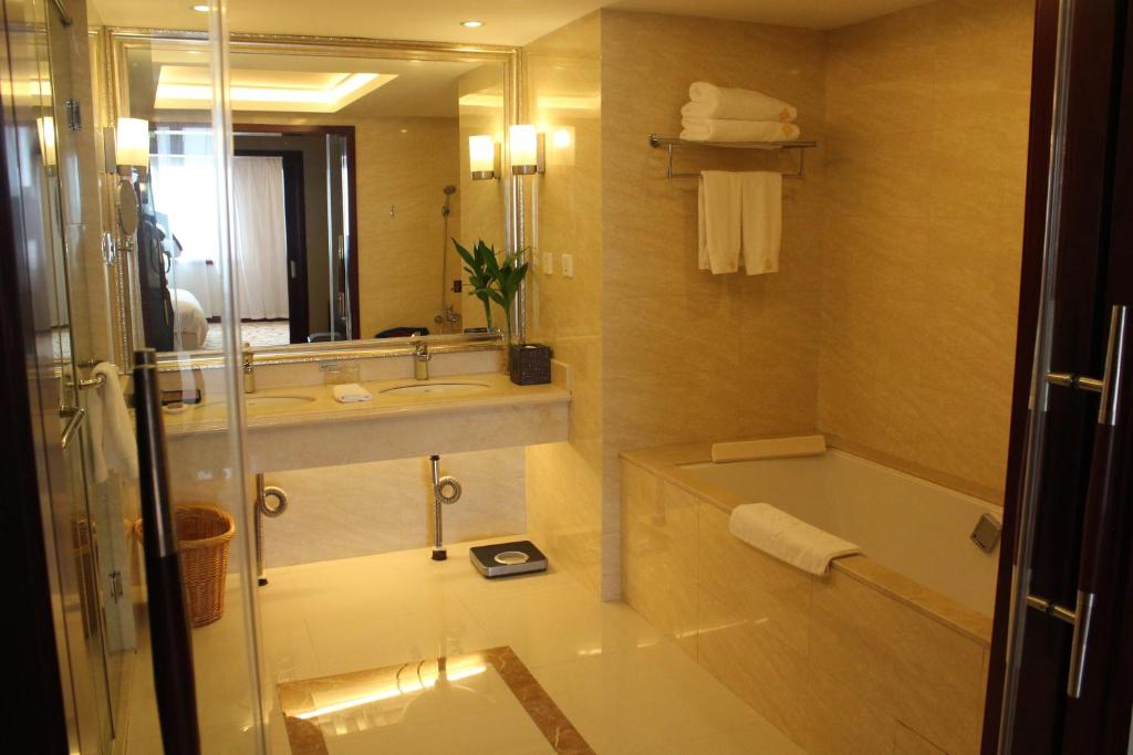 a bathroom with a tub and a sink and a mirror at Jinyuan Jinling Plaza Xuzhou in Xuzhou