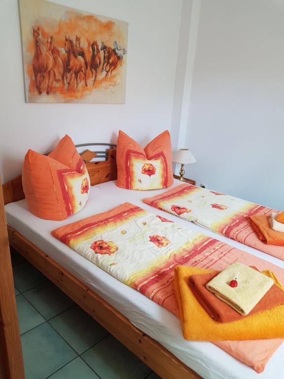 - un lit avec des couvertures et des oreillers orange et blancs dans l'établissement Ferienwohnung Burgenblick, à Thale