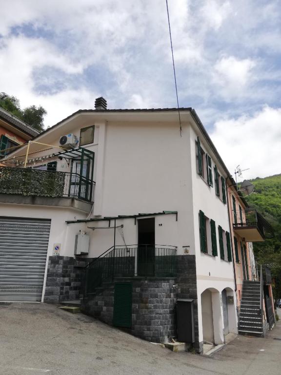a white house with a gate and a balcony at Casa Rosaguta in Vescina