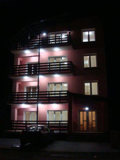 a tall red building with lights on it at night at Olanesti Apartament in Băile Olăneşti