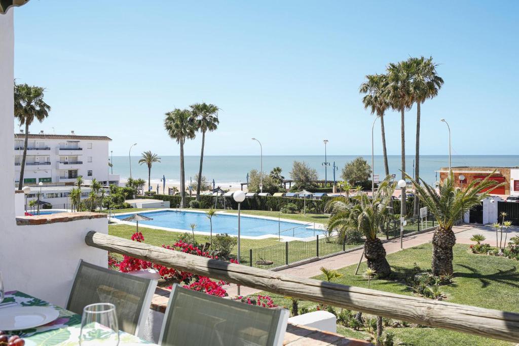 a view of the pool and the ocean from the balcony of a resort at Apartamento en la Barrosa vista mar in Chiclana de la Frontera