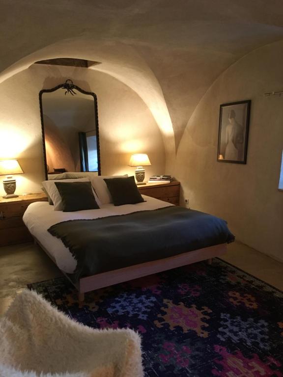 een slaapkamer met een bed met een spiegel en een tapijt bij La Suite Lou in Le Noyer