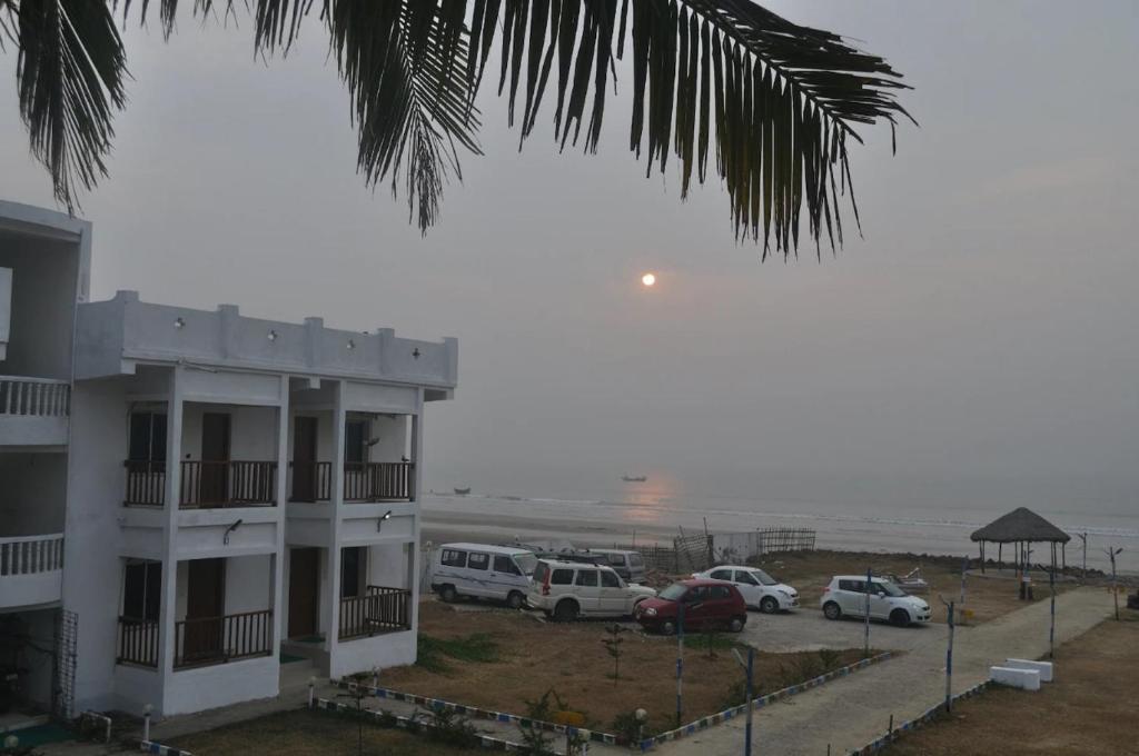 a building with cars parked in front of the beach at Beach Facing Resort Mandarmani in Mandarmoni
