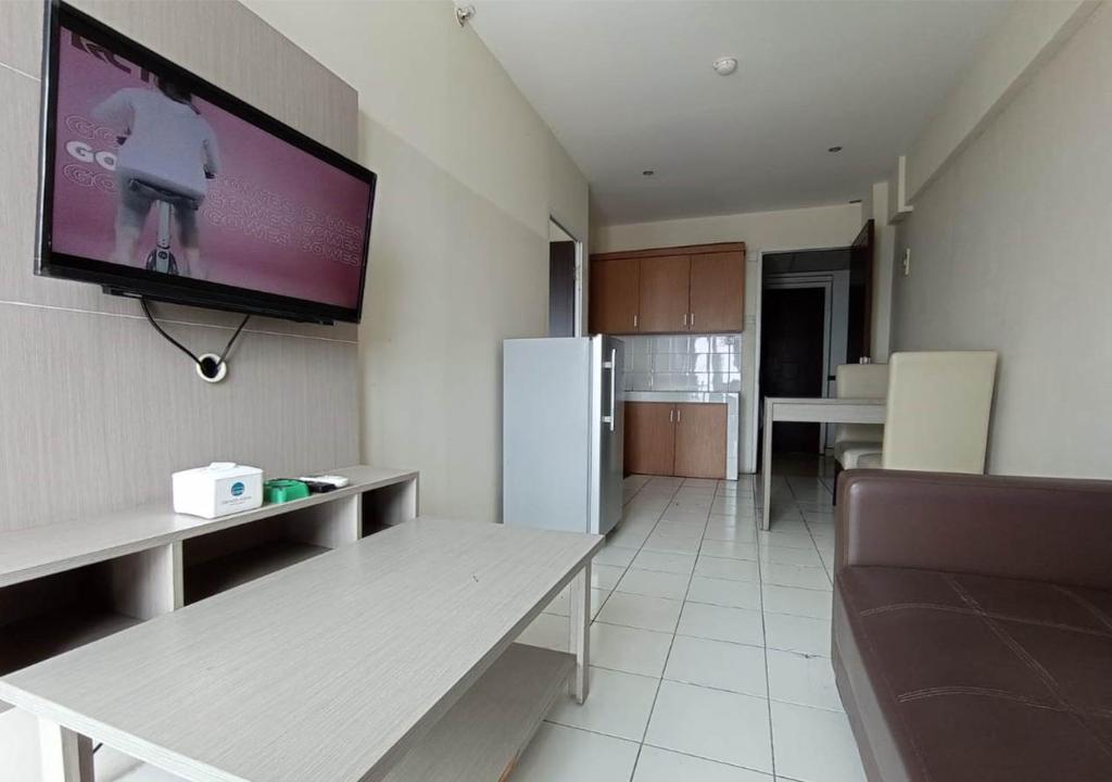 sala de estar con TV de pantalla plana en la pared en X-pressbedroom Mutiara-Bekasi en Bekasi