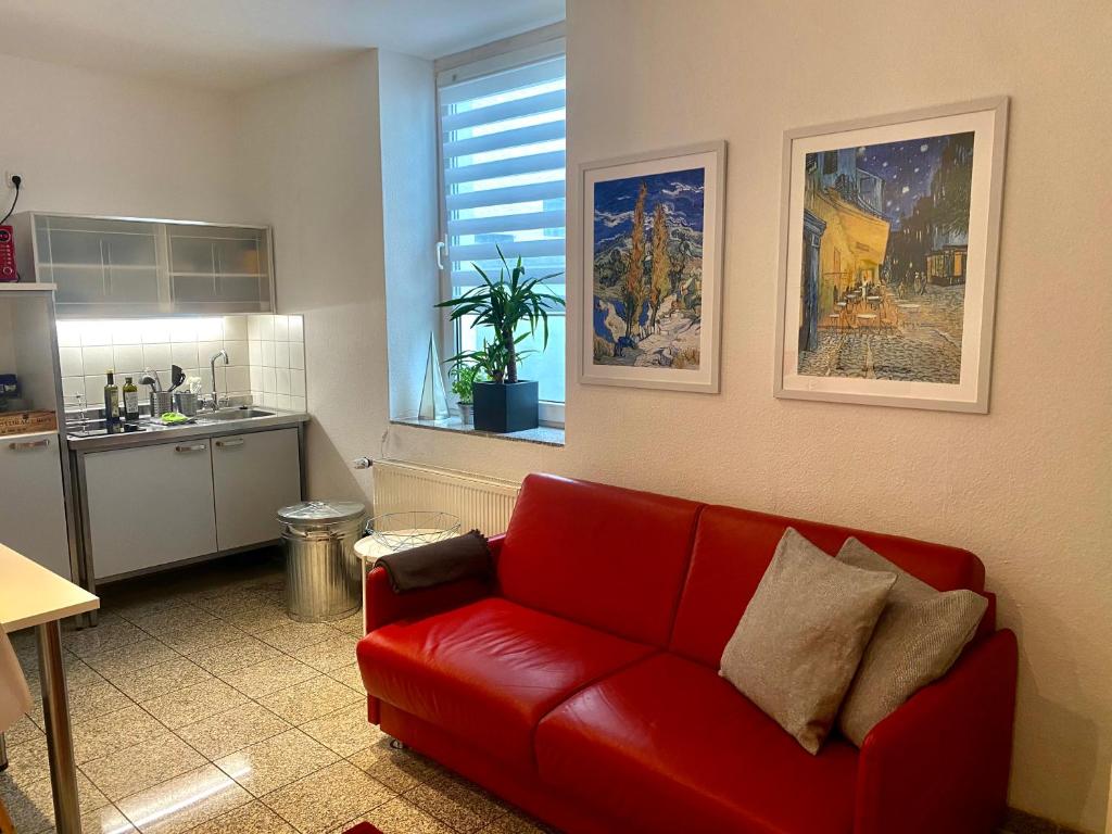 a living room with a red couch and a kitchen at Chez Coco Apartment 1 Aachen in Aachen