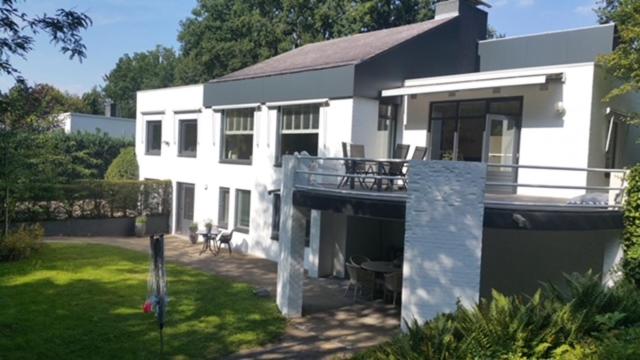 Cette grande maison blanche dispose d'un balcon et d'une cour. dans l'établissement B&B Eikendreef, à Haelen