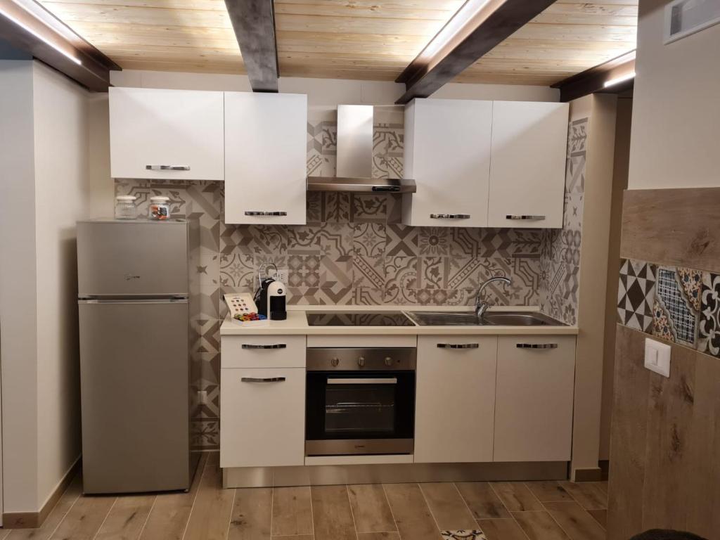  La cuisine est équipée de placards blancs et d'un réfrigérateur. dans l'établissement Elmar, à Bisceglie