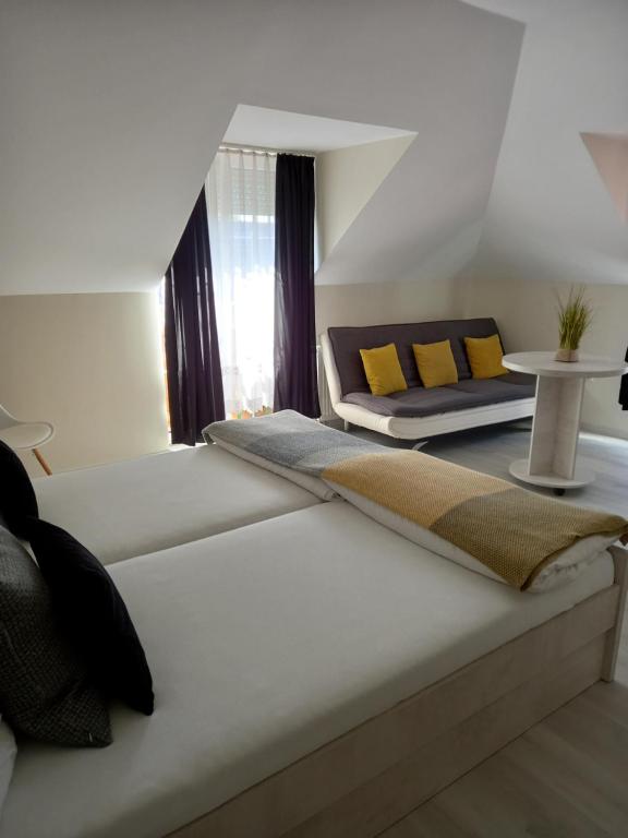 1 dormitorio con cama, sofá y mesa en Viola Vendégház en Pápa