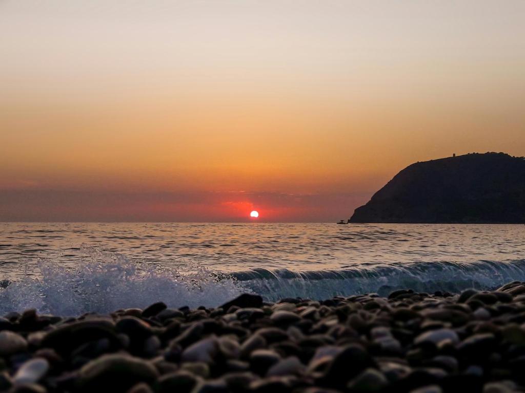 a sunset over the ocean with a rocky beach at Precioso apartamento cerca del mar con wifi, piscina y parking in La Herradura