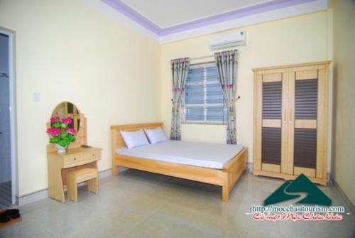 a bedroom with a bed and a table and a window at Nhà nghỉ Dương Vũ in Mộc Châu