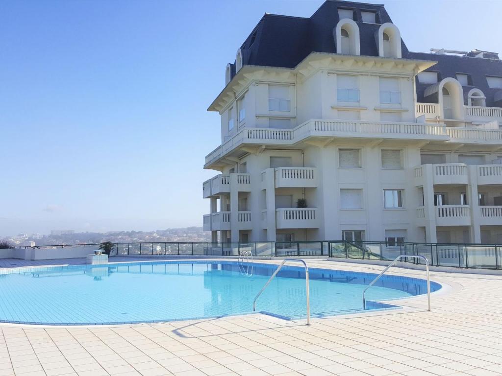 a large building with a large swimming pool in front of it at Apartment Le Palais de la Roseraie by Interhome in Bidart