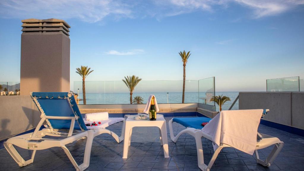 - un balcon avec deux chaises et une table donnant sur l'océan dans l'établissement Apartamentos Buendía, à Puerto de Mazarrón