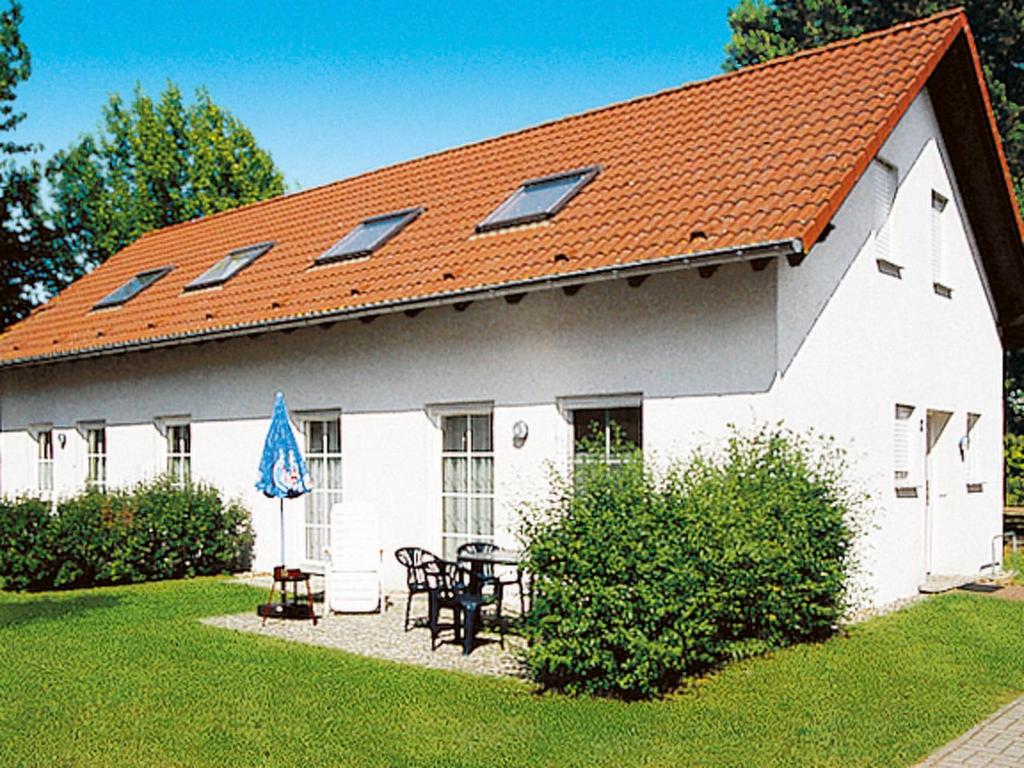 a white building with an orange roof with a table and chairs at Holiday Home Lenzer Höh-2 by Interhome in Lenz