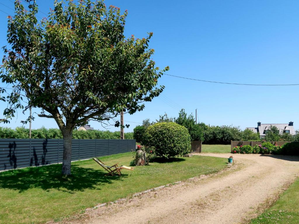a tree sitting in the grass next to a fence at Holiday Home Les Hortensias - KSD101 by Interhome in Kermaria-Sulard