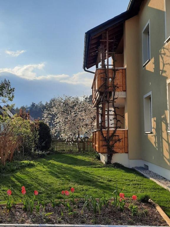 a house with a balcony and a yard with flowers at Ferienwohnung Seenglück in Wackersdorf
